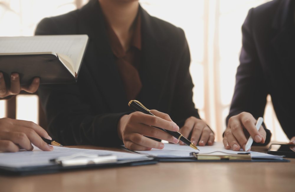 Lawyer, legal advisor, businessman brainstorming information on agreement details Business contracts in legal processing books for accuracy in contract documents. joint financial investment.