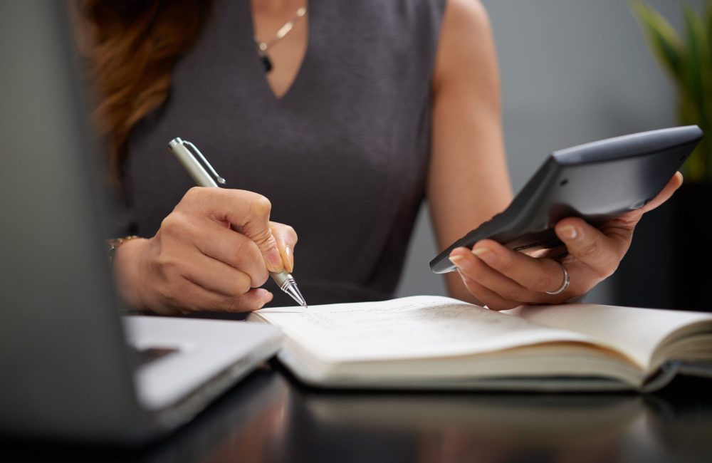 Close-up image of business lady making calculations and taking notes